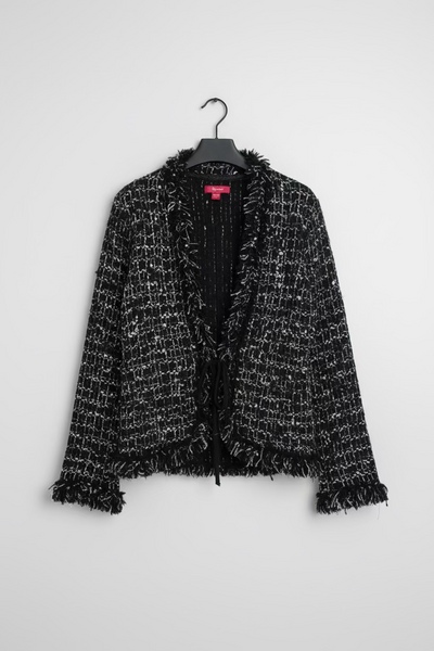 A black and white tweed cardigan with frayed trim, hanging on a black hanger against a grey background